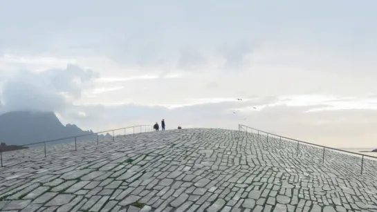Wide stone-paved promenade leading to a distant horizon with small silhouettes, railings, cloudy sky, and birds.