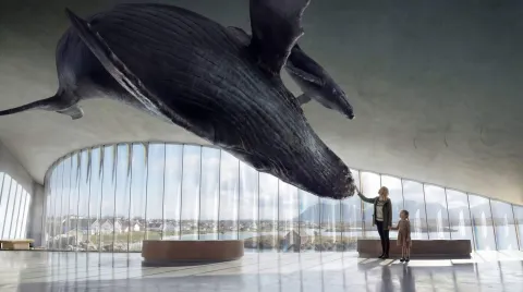 Inside a bright, glass-walled hall, a massive hanging whale sculpture hovers as a woman and child reach toward it.